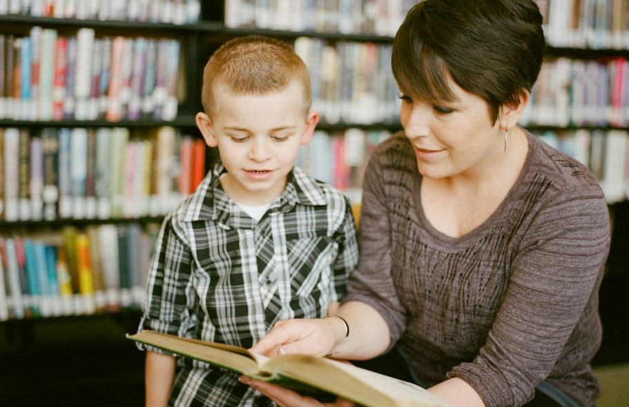 Eine Frau liest einem Jungen in einer Bibliothek vor.