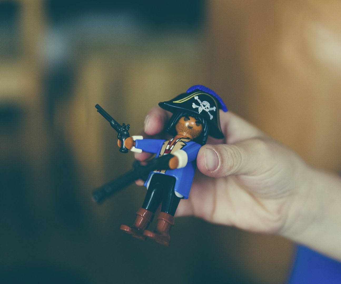 Ein Kind hält eine Piratenfigur mit schwarzer Maske und Waffen in der Hand.